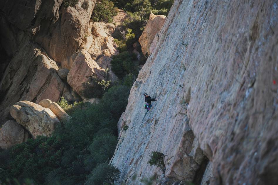 Climbing tricam gear setup on a rocky cliff with mountain backdrop